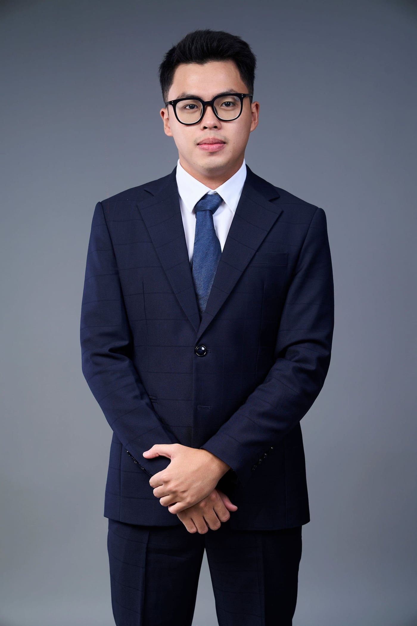 Ảnh profile Co-Founder nam mặc vest xanh navy và cà vạt xanh trên nền xám